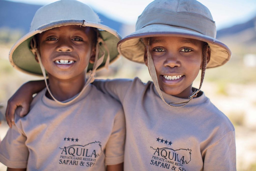Two young children in khaki safari gear standing side-by-side and smiling at the camera.