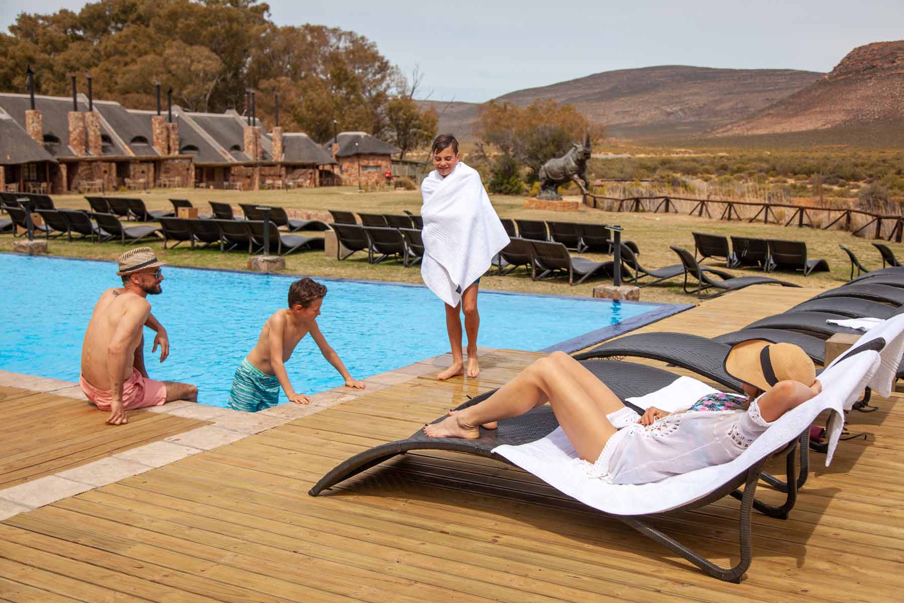 family lounging by Aquila's infinity pool while overlooking the game reserve.